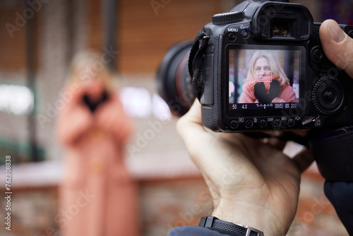 Billede på lærred Display of camera with preview of female portrait in hands of photographer outdoor