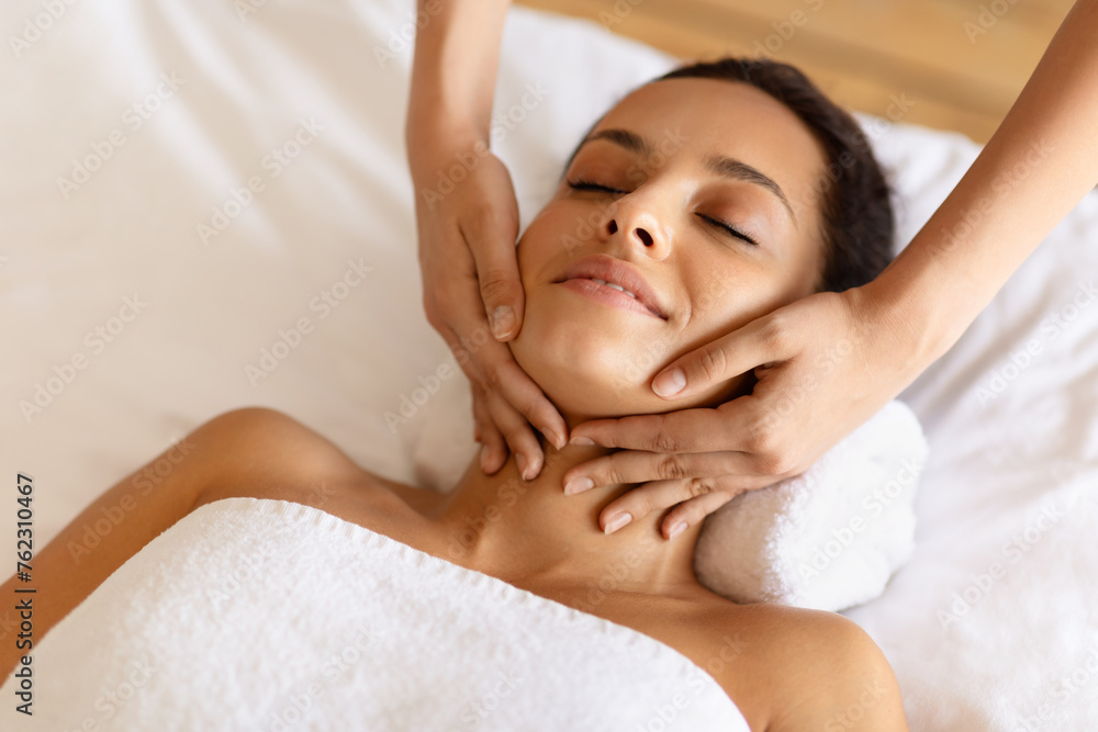 therapist rubbing relaxed woman's chin during facial massage at spa therapist rubbing relaxed woman's chin during facial massage at spa
