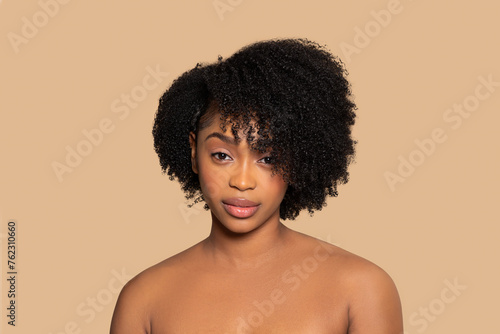 Confident black woman with bushy hair on beige backdrop