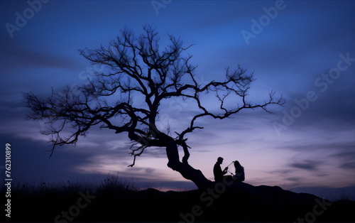 The image is of a couple sitting under a tree at sunset. The sky is blue and orange  and the tree is black. The image is in the art style of silhouette  and the subject is nature.