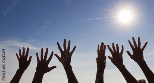 Raised up hands of many people on background of blue sunny sky closeup