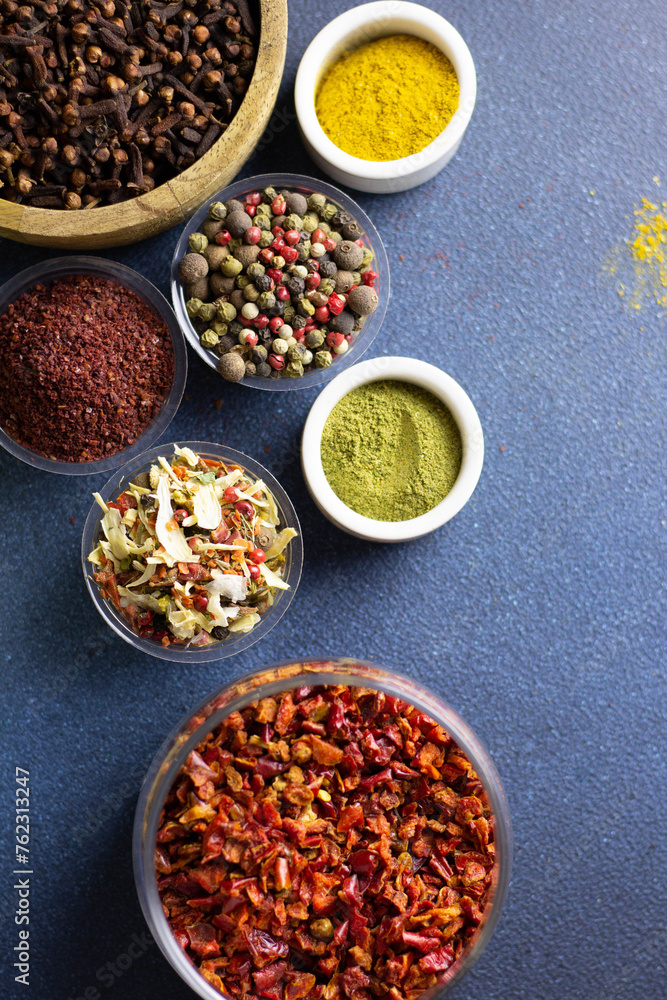 vertical photo of different spices, aromatic spices, spices for the kitchen, on a blue background, copy space vertical photo of different spices, aromatic spices, spices for the kitchen, on a blue background, copy space