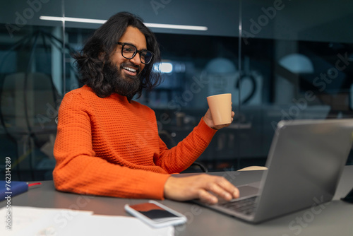 Bild auf Leinwand Man holding cup while working on laptop