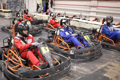 Five adults and one child in helmets prepares for driving karting photo
