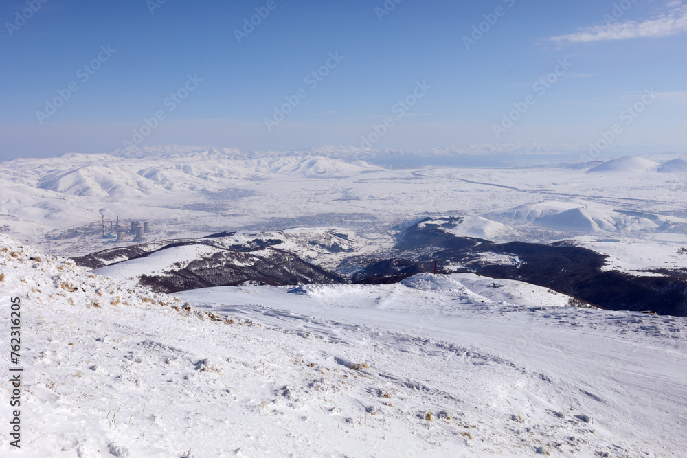 Beautiful mountains in snow in ski resort, power plant, Sevan lake far away, Tsakhkadzor, Armenia in winter sunny day