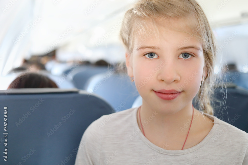 Smiling blonde girl looks at camera in flying aircraft, shallow dof Smiling blonde girl looks at camera in flying aircraft, shallow dof