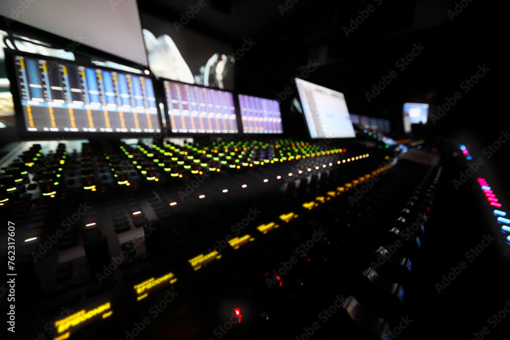 Dark recording studio with modern equipment, cinema display out of focus