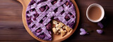 Food photography of a blueberry pie made of puzzle pieces with missing pieces on a table with a cup of tea and purple flowers.