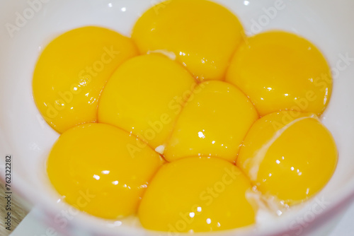 Yellow fresh egg yolks in white plate for cooking, close up view
