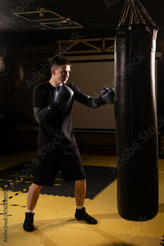 Full length view of young male boxer training with punching bag in he gym. © mtrlin
