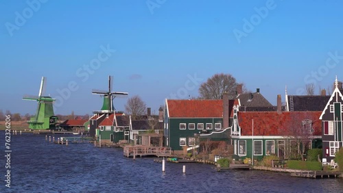Beautiful Dutch scenery panorama of Zaanse Schans village in Netherlands in spring time. Ancient windmills at the Zaan river against a blue sky in sunny weather photo