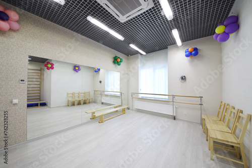 Empty lit gym with big mirror  chairs in kindergarten for children