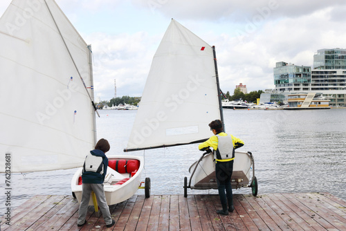 Two boys put afloat small yachts to lake in Yacht club on Voykovskaya