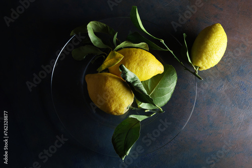 Limoni su un piatto; still life con vista dall’alto, composizione su fondo scuro photo
