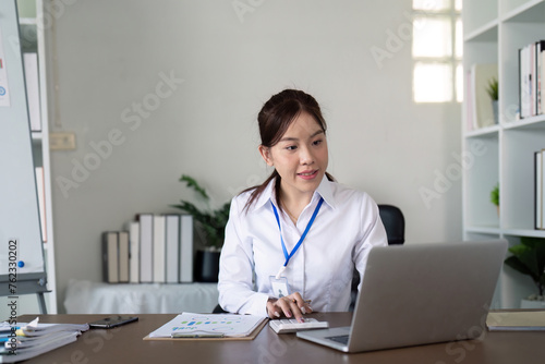 Asian business woman using laptop to analysis graph financial budget report and planning for future in office desk