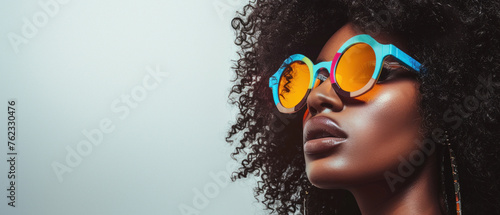 Close-up of a fashionable woman with voluminous afro hair sporting reflective orange sunglasses, showcasing style and confidence
