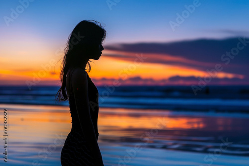 Silhouette of Young woman standing on beach at sunset.