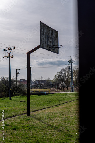 Old abandoned basketball court. Spring is coming, and green grass around.