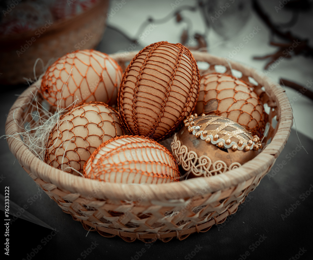 Easter decorative eggs in a basket nest with straw background