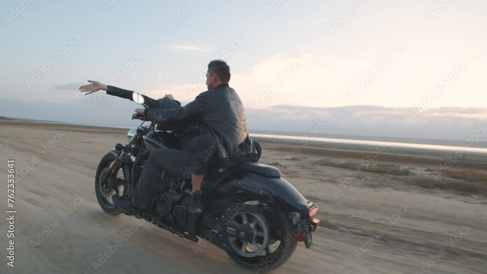 Guy with a girl on a motorcycle in the desert. Couple riding on vintage motorcycle and having a good time at sunset on a dry salt lake. Slow motion shot Guy with a girl on a motorcycle in the desert. Couple riding on vintage motorcycle and having a good time at sunset on a dry salt lake. Slow motion shot