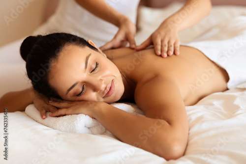 woman enjoying massage and calming touch of masseuse's hands indoor