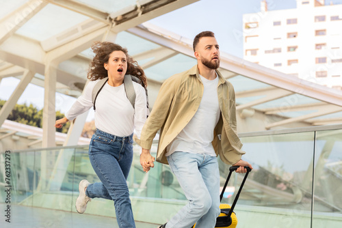 Canvas Print Stressed young couple running in airport terminal, late for their flight