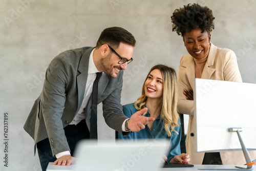 Group of multiethnic business people analyzing data using computer while working in the office
