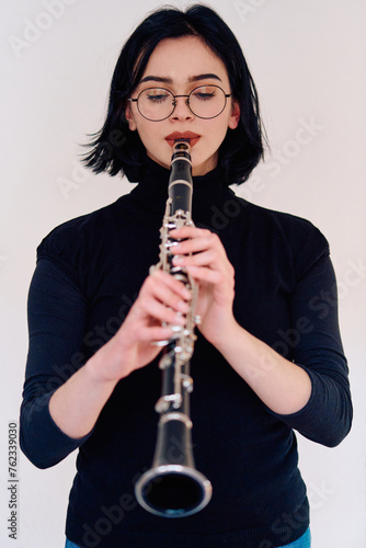 Graceful Brunette Musician Posing with Clarinet on White Background photo