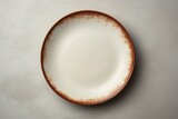 Simple white plate with a brown rim on a wooden table. Suitable for food or kitchen related concepts