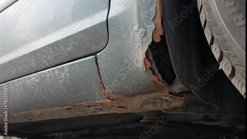 fragment of a rusty wing of a car. Fragment of a car body with rust.  The body element is corroded. Concept: corrosion resistance, body repair, rust. Protection.