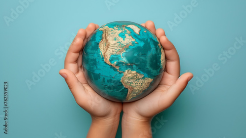 Earth globe planet in kid's tender hands against blue background with copy space. World environment day, Earth world protection concept.
