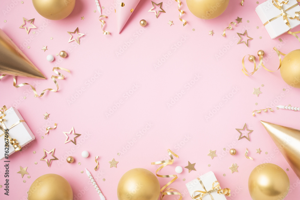 Birthday party festive background with golden decoration from gift box, balloons, carnival hat, confetti on pastel pink table top view.