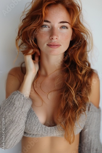 Beautiful white woman with red hair, happy and smiling while touching her neckline against a white background. She is wearing. Trendy model posing for a beauty concept