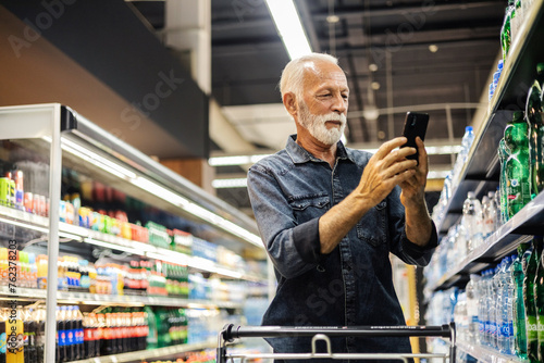 Customer scanning a product at wholesale while using his smartphone. The male customer takes a picture of the product and sends it to someone.