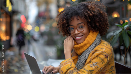 Mixed race attractive woman wearing glasses look at pc screen typing business letter informal e-mail chatting with friend online, african female freelancer sitting at table working on computer at home photo