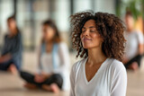 wellness yoga meditation concept, ,A woman with curly hair is sitting in a group of people, all of them looking at the camera. The woman is smiling and she is in a relaxed and peaceful state