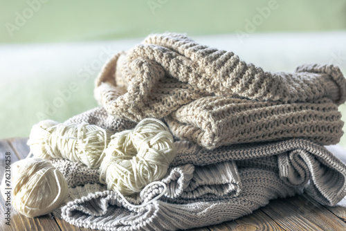 Stack of cozy knitted sweaters on wooden background.