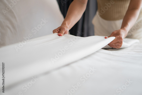 Foto Housewife set up white sheet and cleaning in room. Housewife