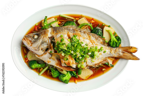 Chinese style fish dish: whole fish steamed with ginger, green onions and soy sauce, served with steamed rice and vegetables on a white platter.