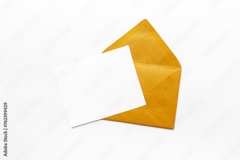 Blank white paper on the golden envelope. Mockup of letter or greeting card. Top view Blank white paper on the golden envelope. Mockup of letter or greeting card. Top view