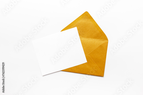 Blank white paper on the golden envelope. Mockup of letter or greeting card. Top view