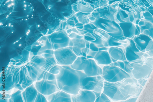 Top view of the water in the pool. Blue water background with sun glare.