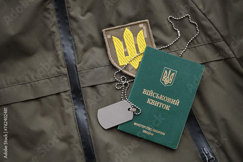 Military token or army ID ticket lies on green ukrainian military uniform indoors close up photo