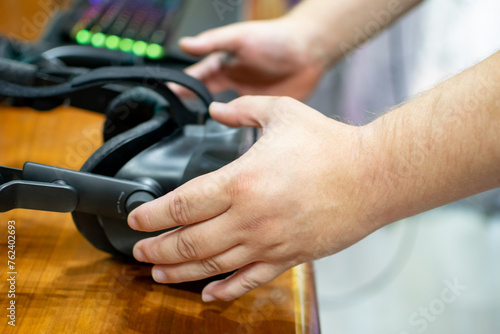 Close up image of hands picking up VR goggles with illuminated keyboard © CarlosMSubirats