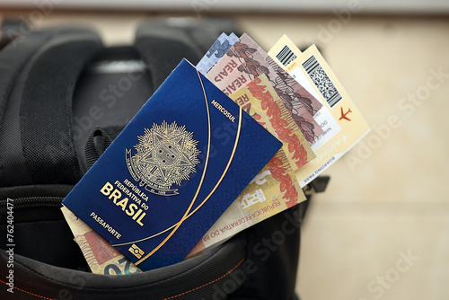 Blue Brazilian passport with money and airline tickets on touristic backpack close up. Tourism and travel concept photo