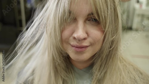 close-up of a woman's face in a beauty salon, the master dries her hair with a hairdryer after a haircut, beautiful long blond long hair