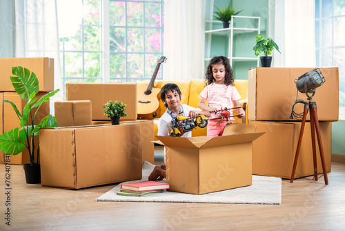 Indian siblings or kids playing or opening cardboard cartons on shifting or moving day