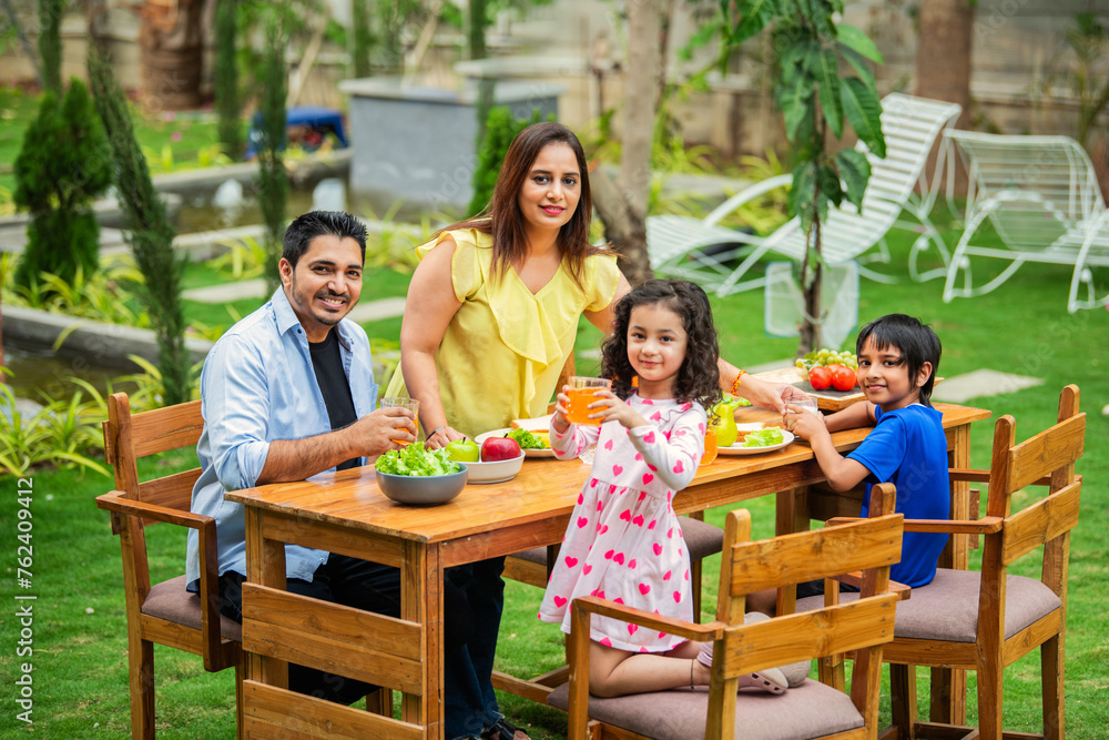 Indian couple and kids Enjoying Family Meal in the garden dining table