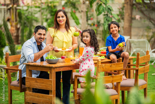 Indian couple and kids Enjoying Family Meal in the garden dining table