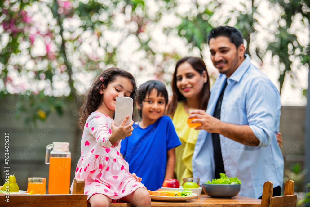 Indian couple and kids Enjoying Family Meal in the garden dining table Indian couple and kids Enjoying Family Meal in the garden dining table